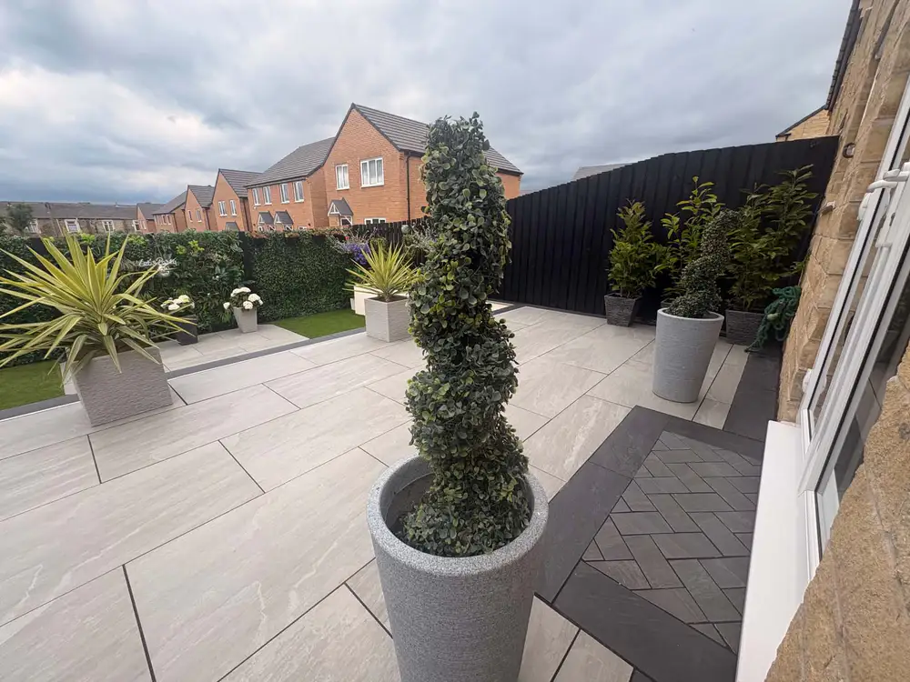 Pale contemporary patio with dark edging, large white planters and a spiral topiary in a grey pot